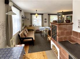 Kuchyně a obývací pokoj s jídelním stolem, rozkládací pohovkou a plně funkčními kachlovými kamny